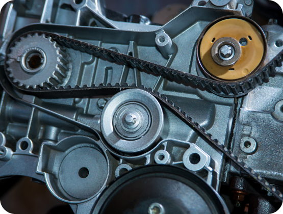 Close-up of an engine with a black timing belt, gears, and pulleys in a metallic gray setting | Hornick's Diesel & Auto Repair