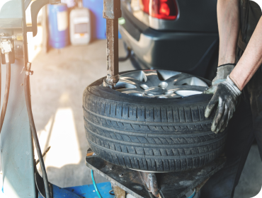 Car wheel undergoing alignment check. A black and white grid attached to the wheel. Red car in a service bay | Hornick's Diesel & Auto Repair
