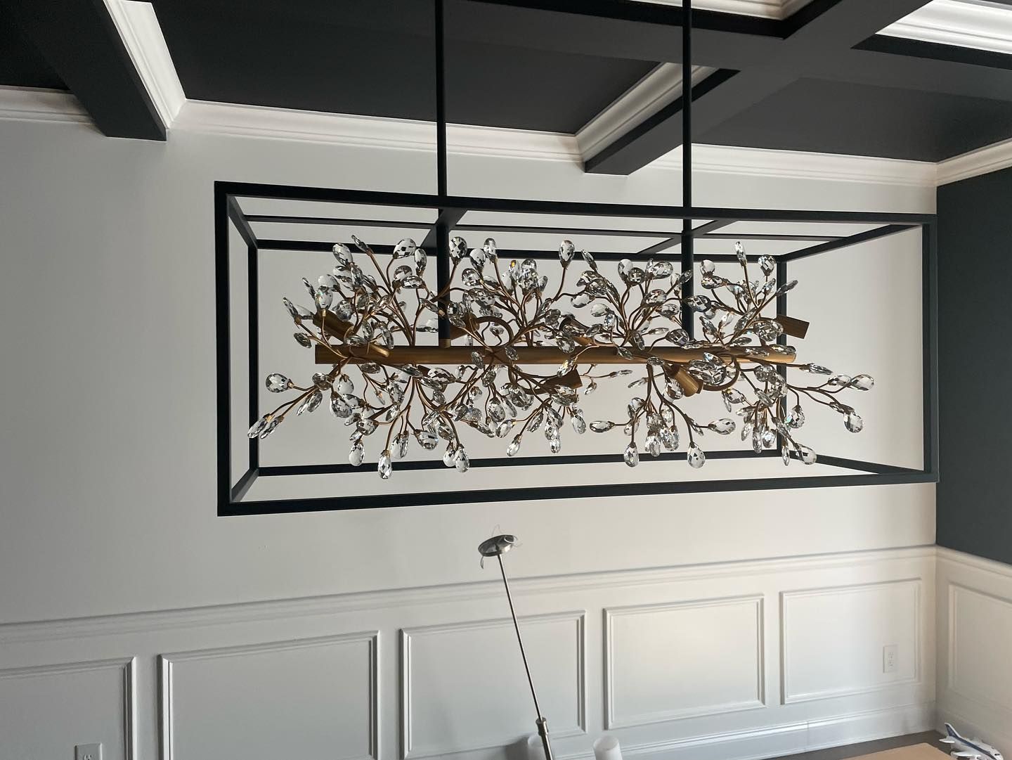 Dining room with chandelier, gold accents, black and white walls, dark ceiling.