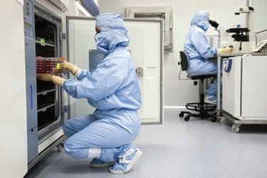 Two people are working in a clean room in a lab.