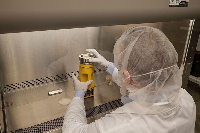 A man in a lab coat is holding a yellow container.