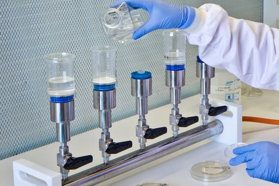 A person is pouring liquid into a glass in a laboratory.