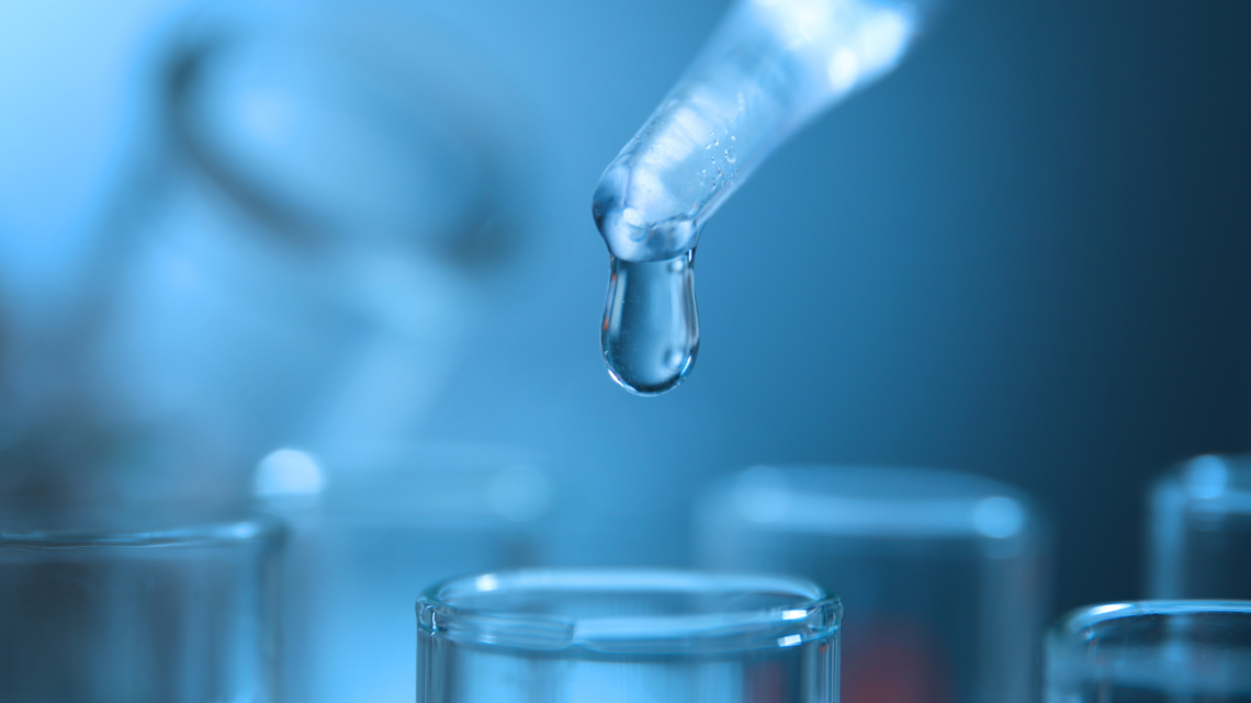 A drop of liquid is being poured from a pipette into a test tube.