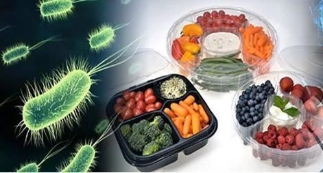 A picture of bacteria next to a tray of vegetables and fruits.