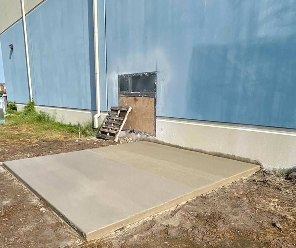 A concrete slab is sitting in front of a blue building.