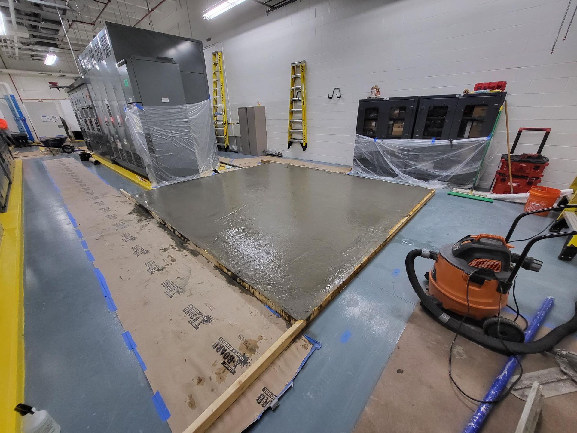 A vacuum cleaner is sitting on a concrete floor in a room.
