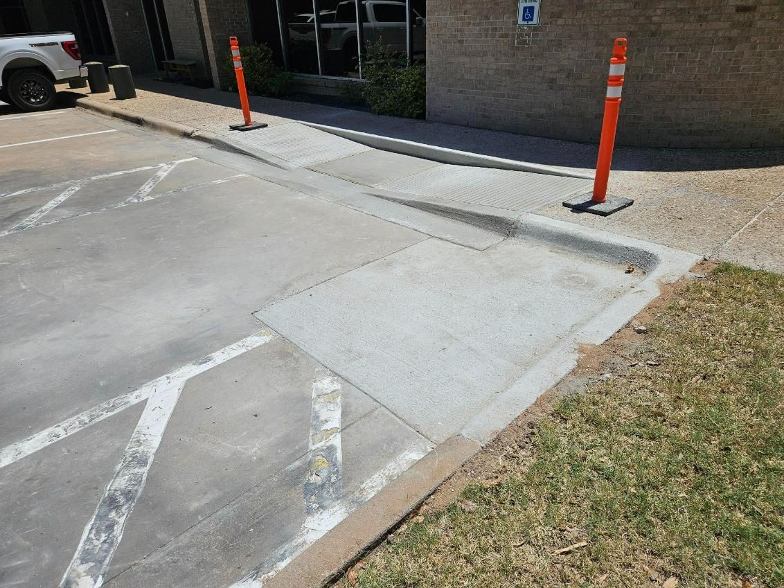 A white truck is parked in a parking lot next to a sidewalk.