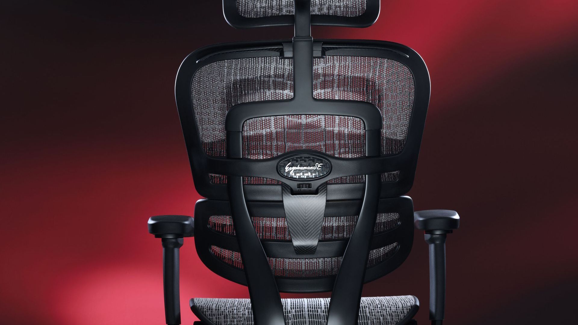 The back view of the Ergohuman Carbon gaming chair against a red background. 