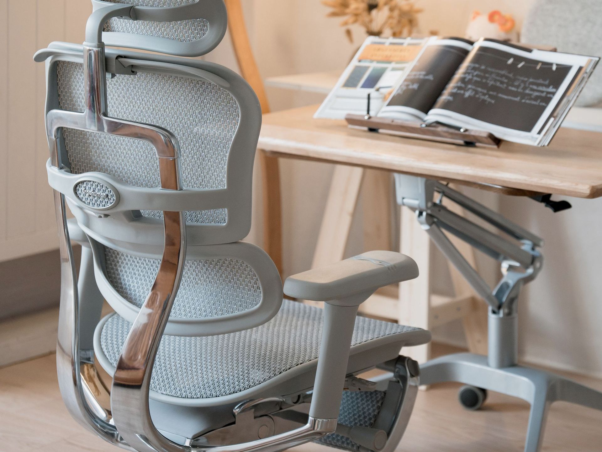 grey ergohuman elite office chair situated at a wooden desk with a book open on the book stand. 