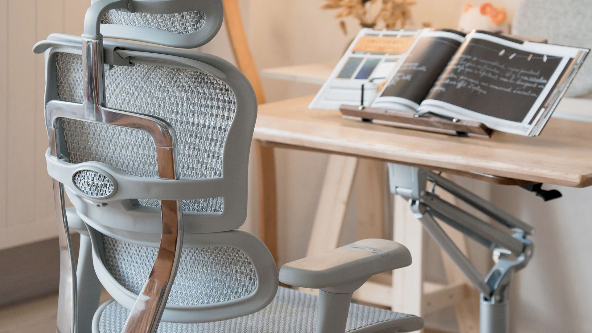 Grey ergohuman elite office chair in a grey frame situated at a desk with an open book 