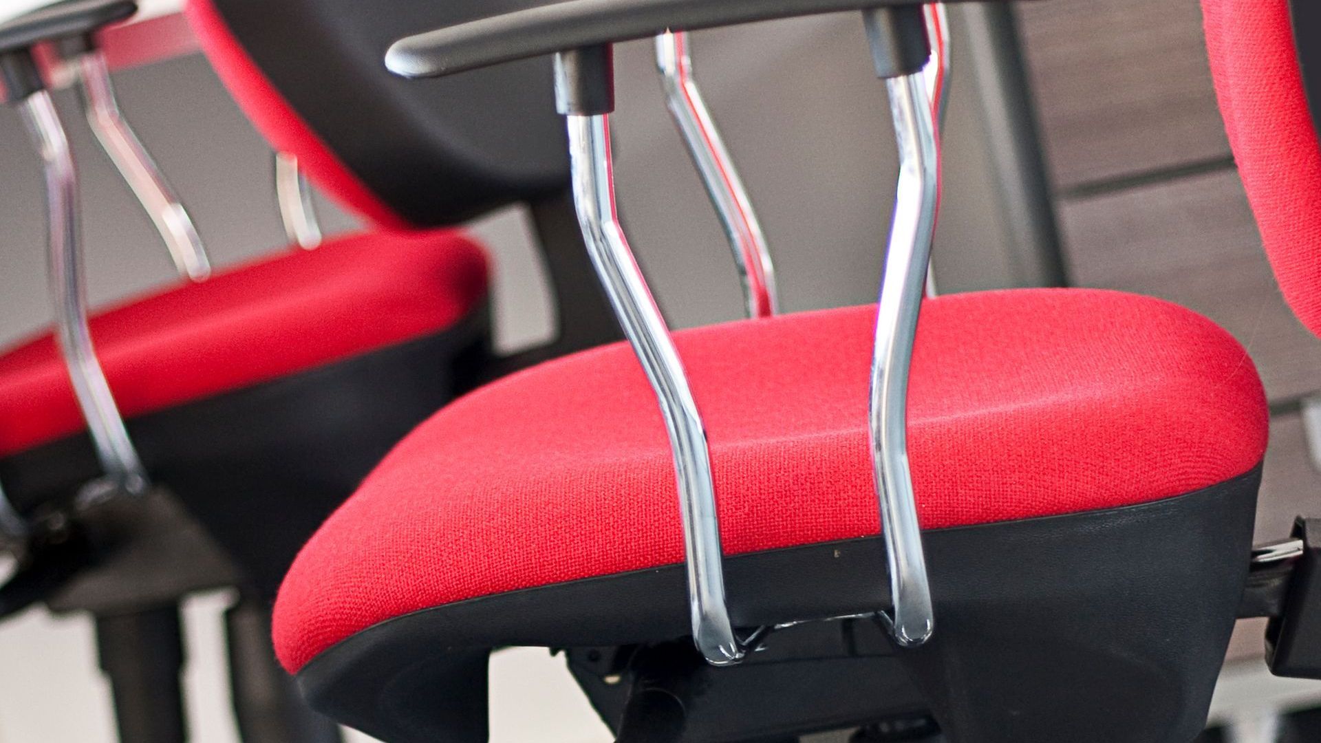 Close up of a red fabric chair. The arms are silver and black. 