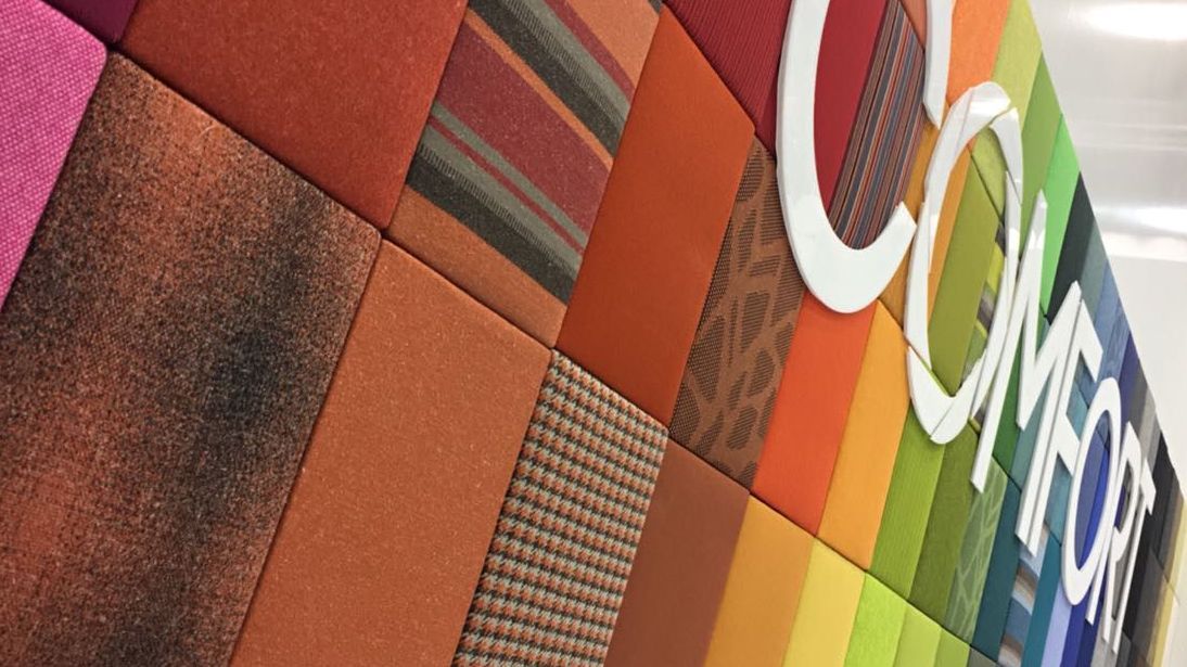 A spectrum of upholstered tiles showing mesh and fabric options with Comfort Seating's logo mounted