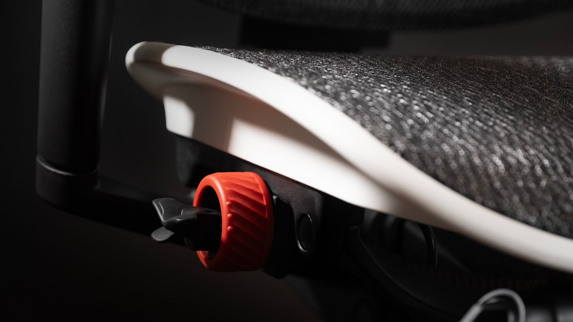 Close up of a mesh gaming chair's lever to adjust seat height, depth and back recline.