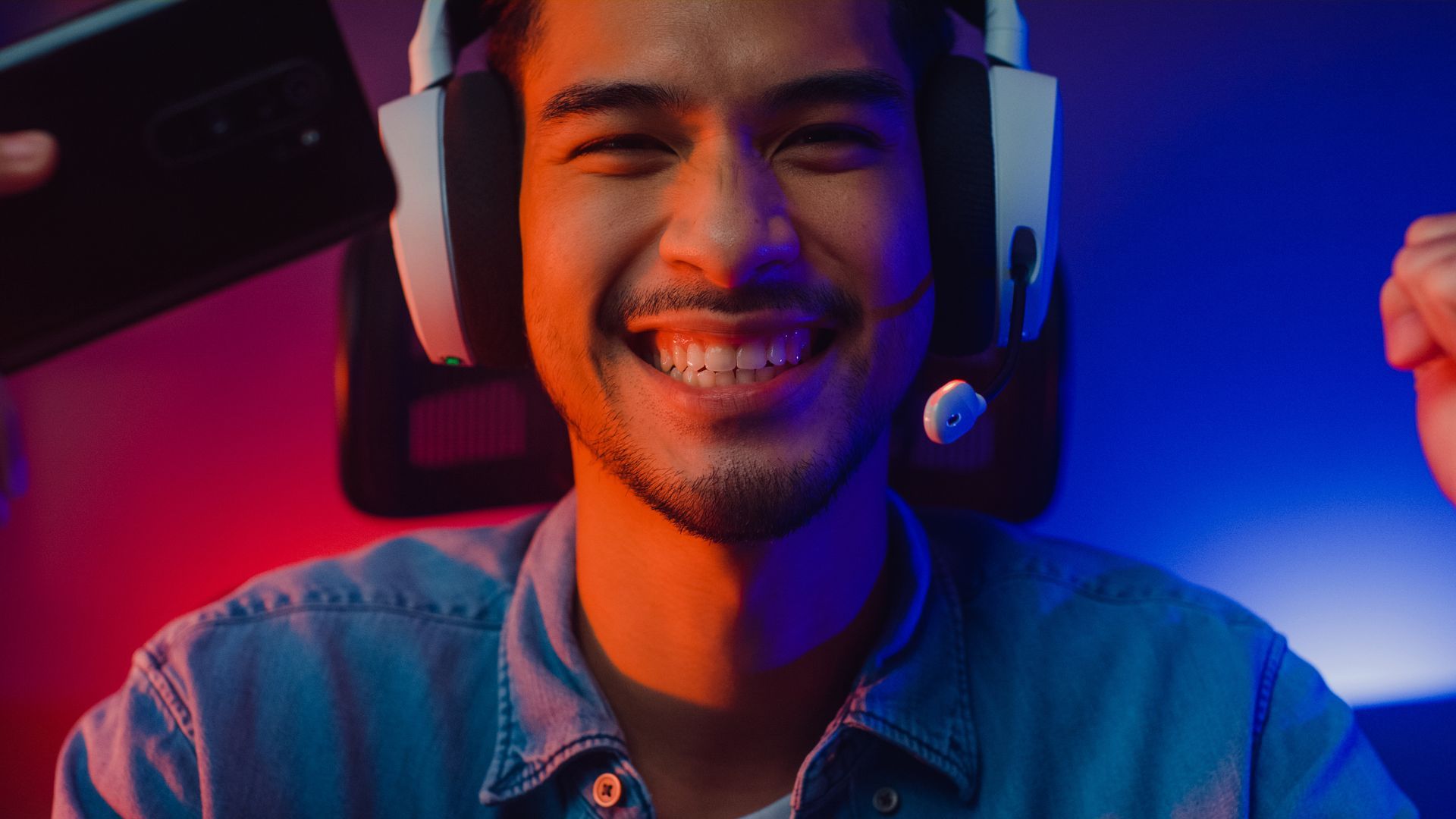 a man wearing gaming headphones looking into the camera smiling. he sits on the ergohuman chair
