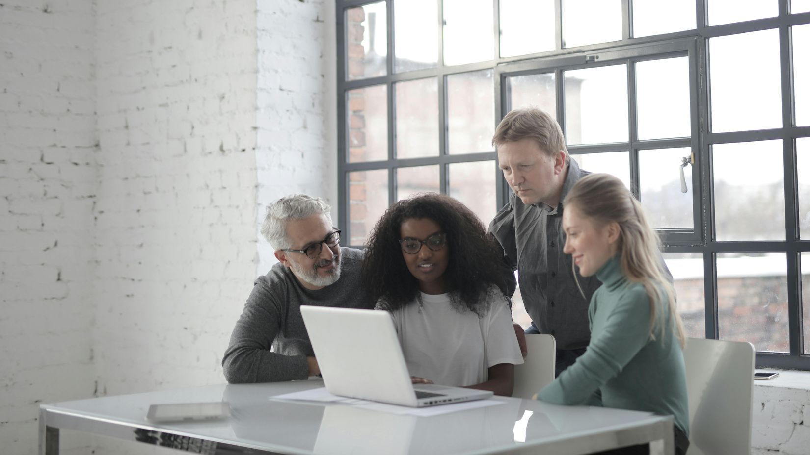 Four business people gather around a laptop on a table for a productive and collaborative meeting