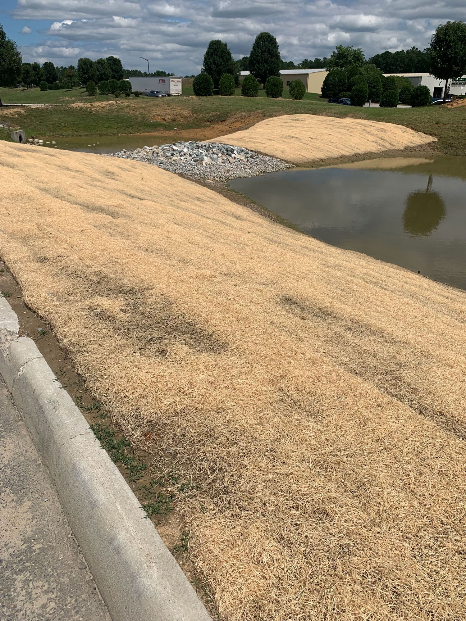 Construction site: small excavator and workers in safety vests, building a ramp.