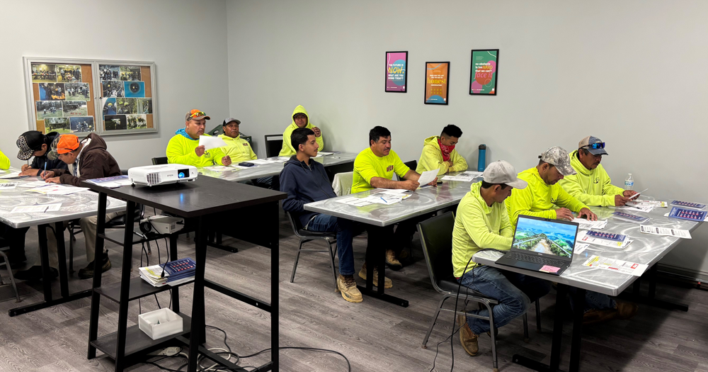 A group of men are sitting at tables in a classroom.