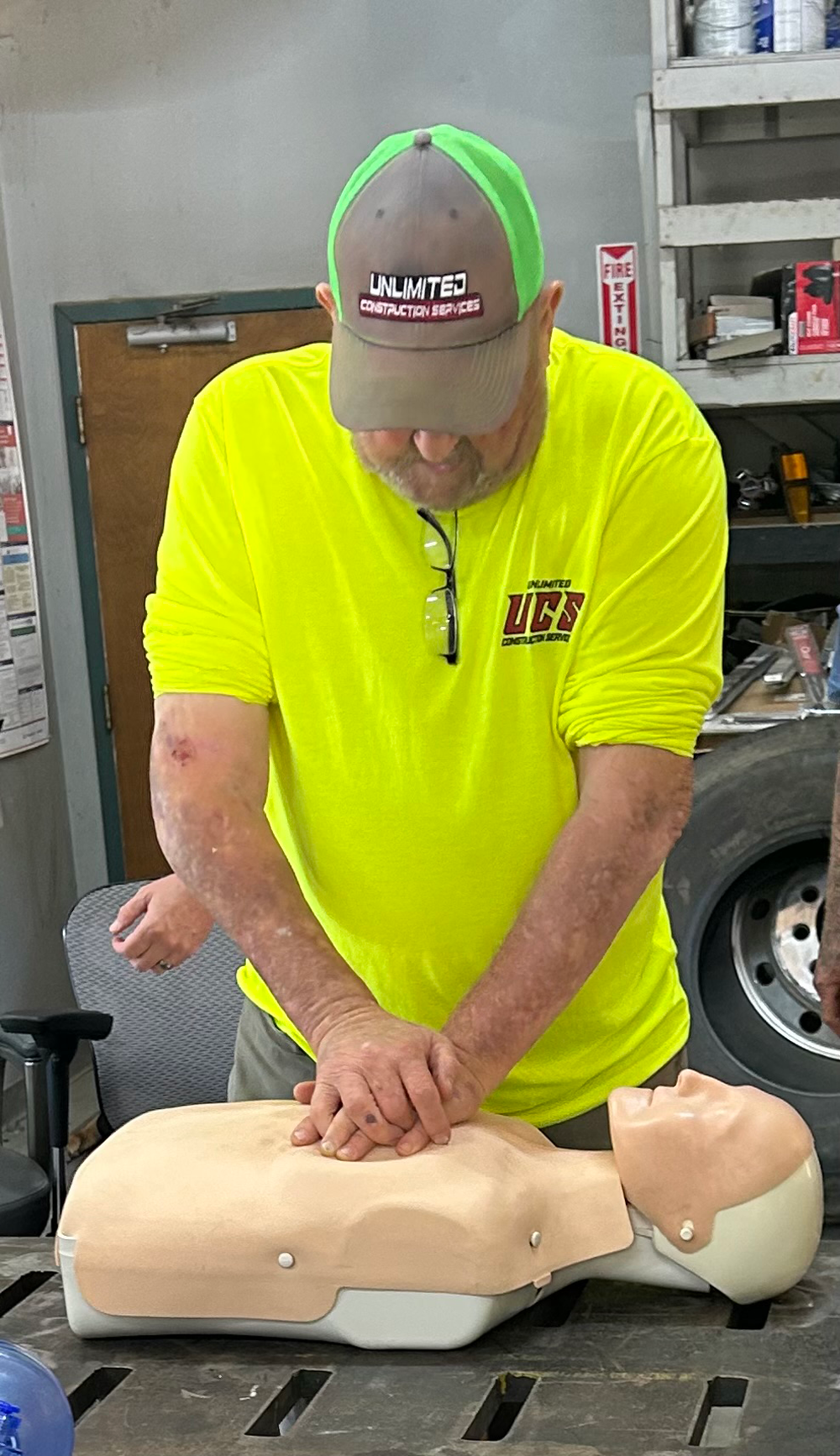 Man in yellow shirt practices CPR on a training dummy.