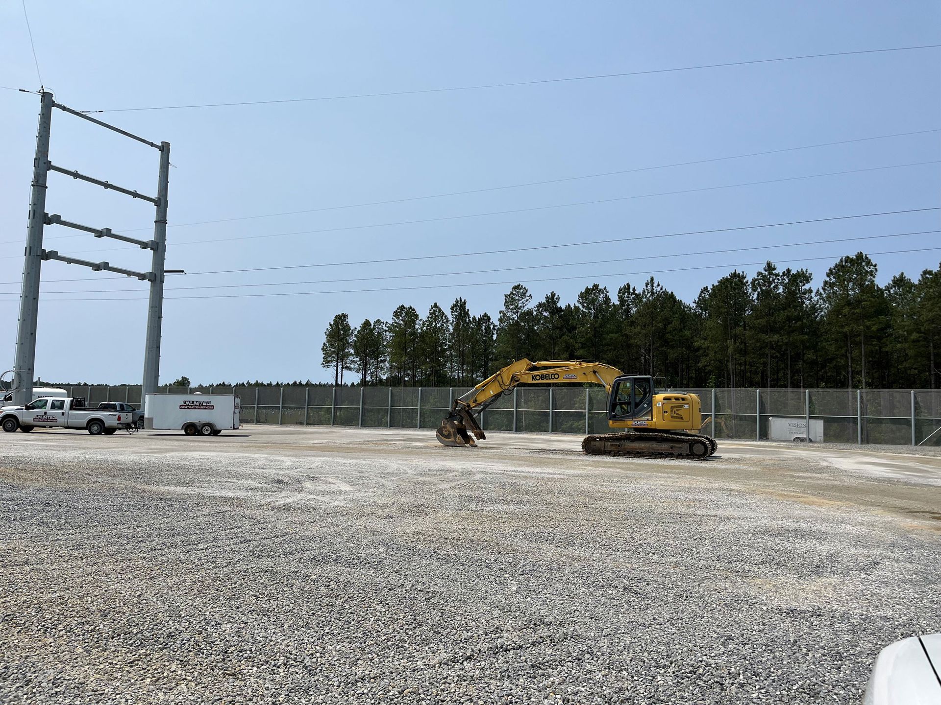 Construction site with an excavator and power line tower.