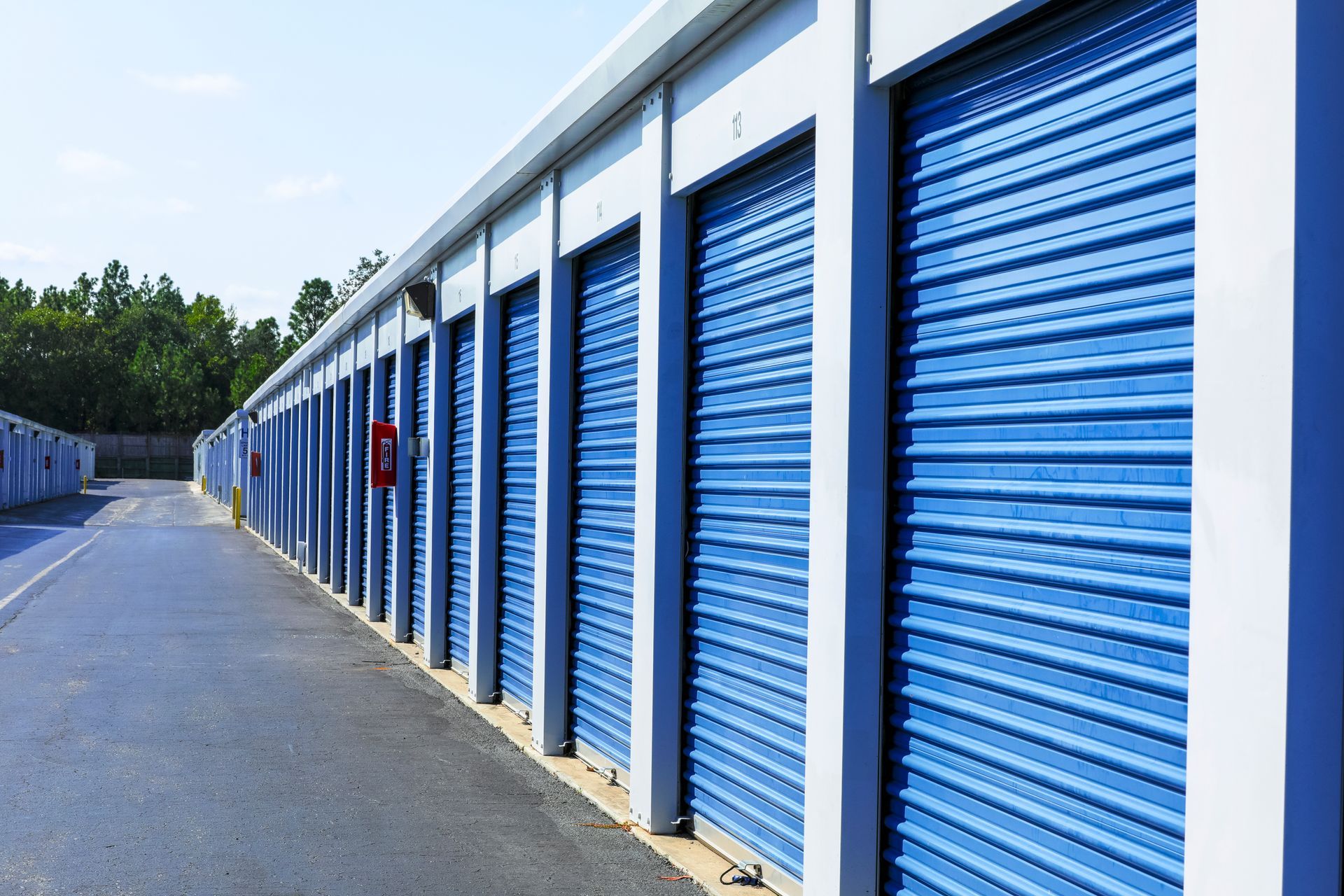 Row of blue roll-up doors at an outdoor self-storage facility. Row of blue roll-up doors at an outdoor self-storage facility.