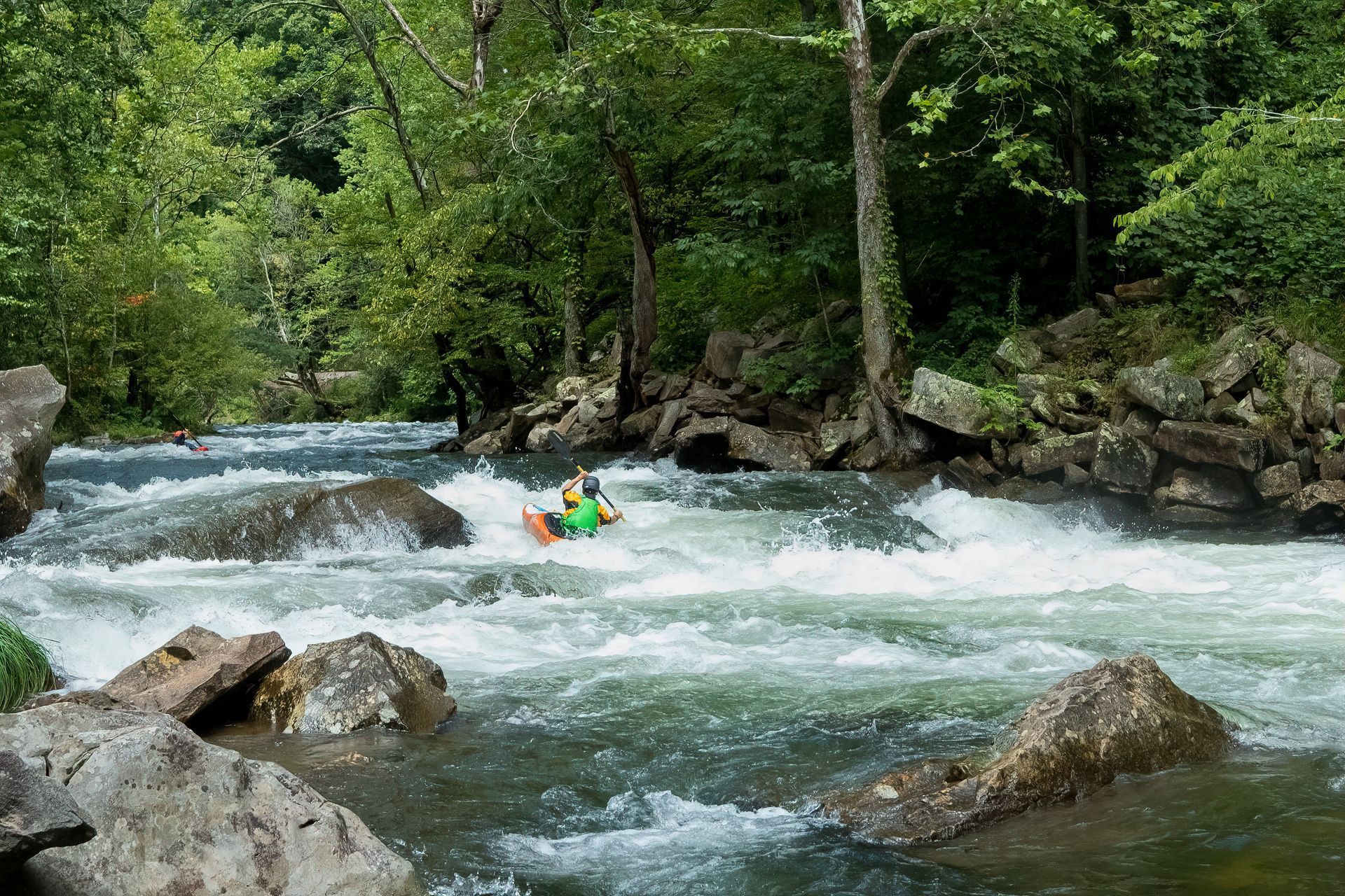 A person is riding a kayak down a river.