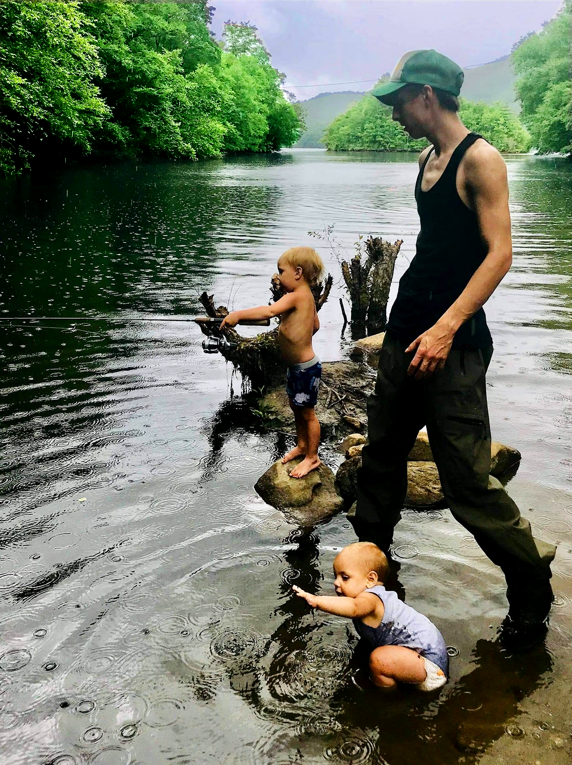 A man and two children are playing in the water
