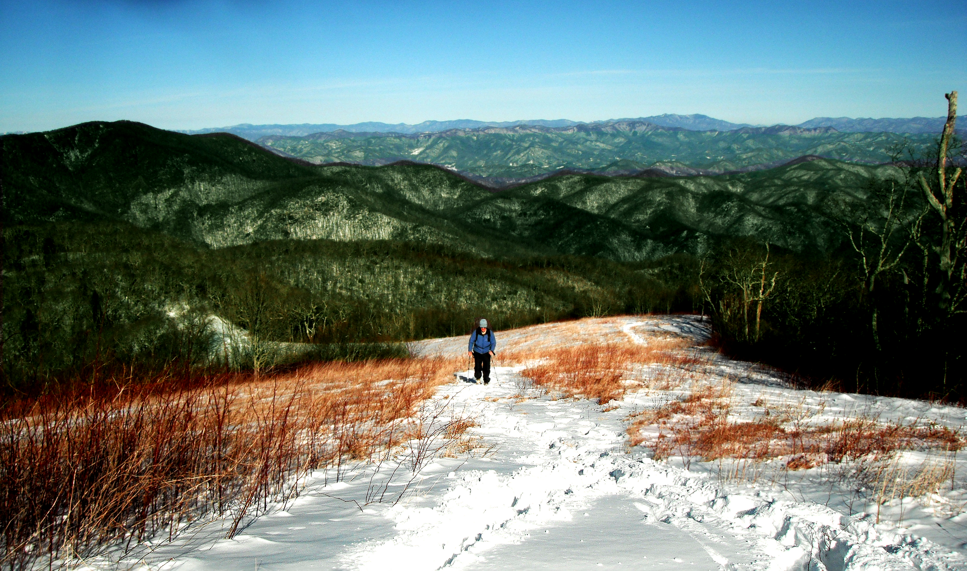 A person walking on a snowy path with mountains in the background