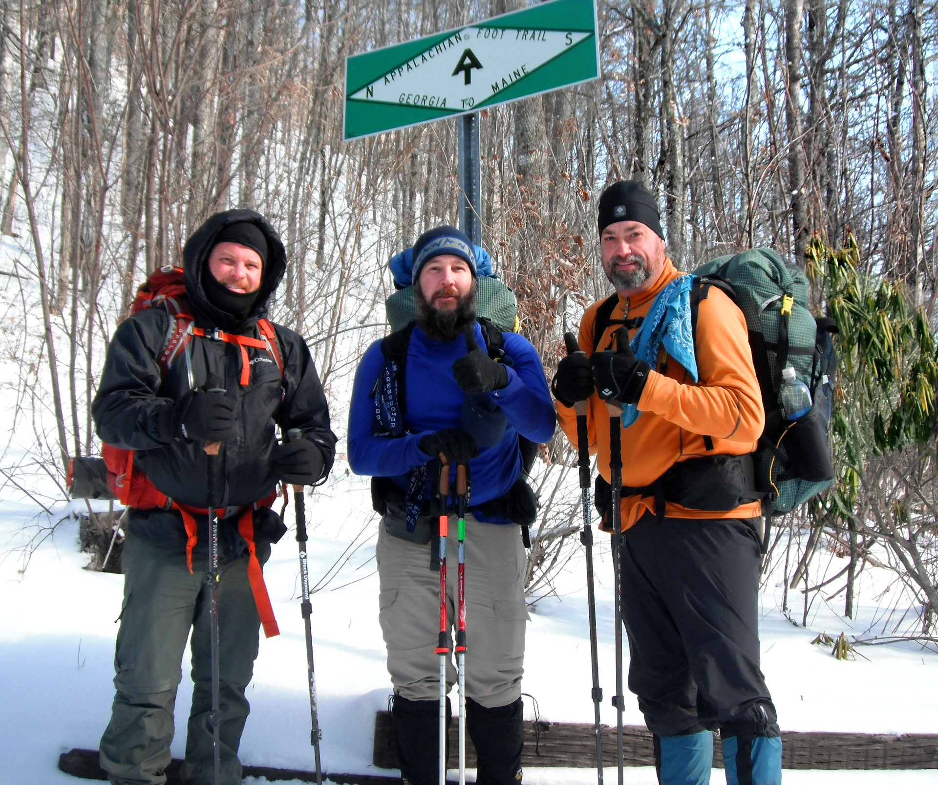 Three men standing in front of a sign that says ' arrow ' on it