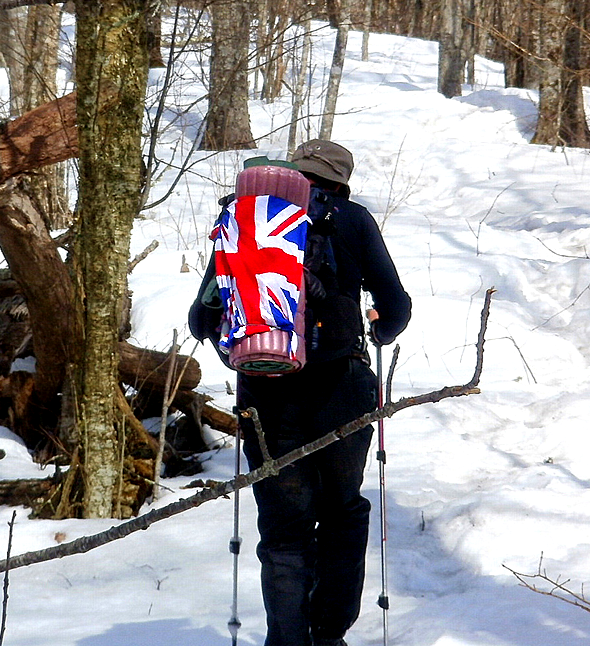 A person walking in the snow with a british flag backpack