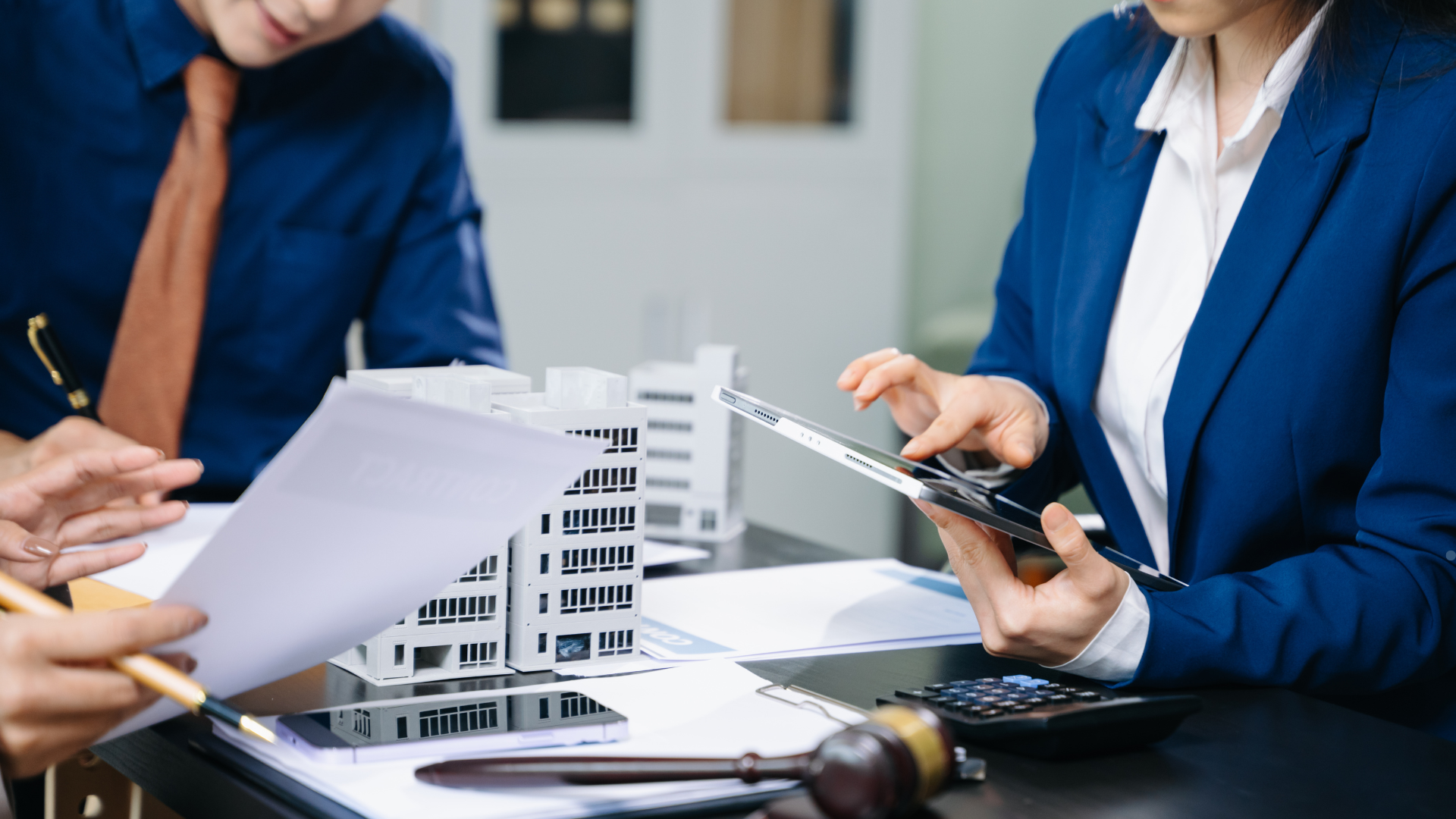 Business professionals reviewing architectural plans and documents, discussing project details with 
