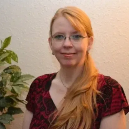 A woman wearing glasses and a red shirt is smiling for the camera