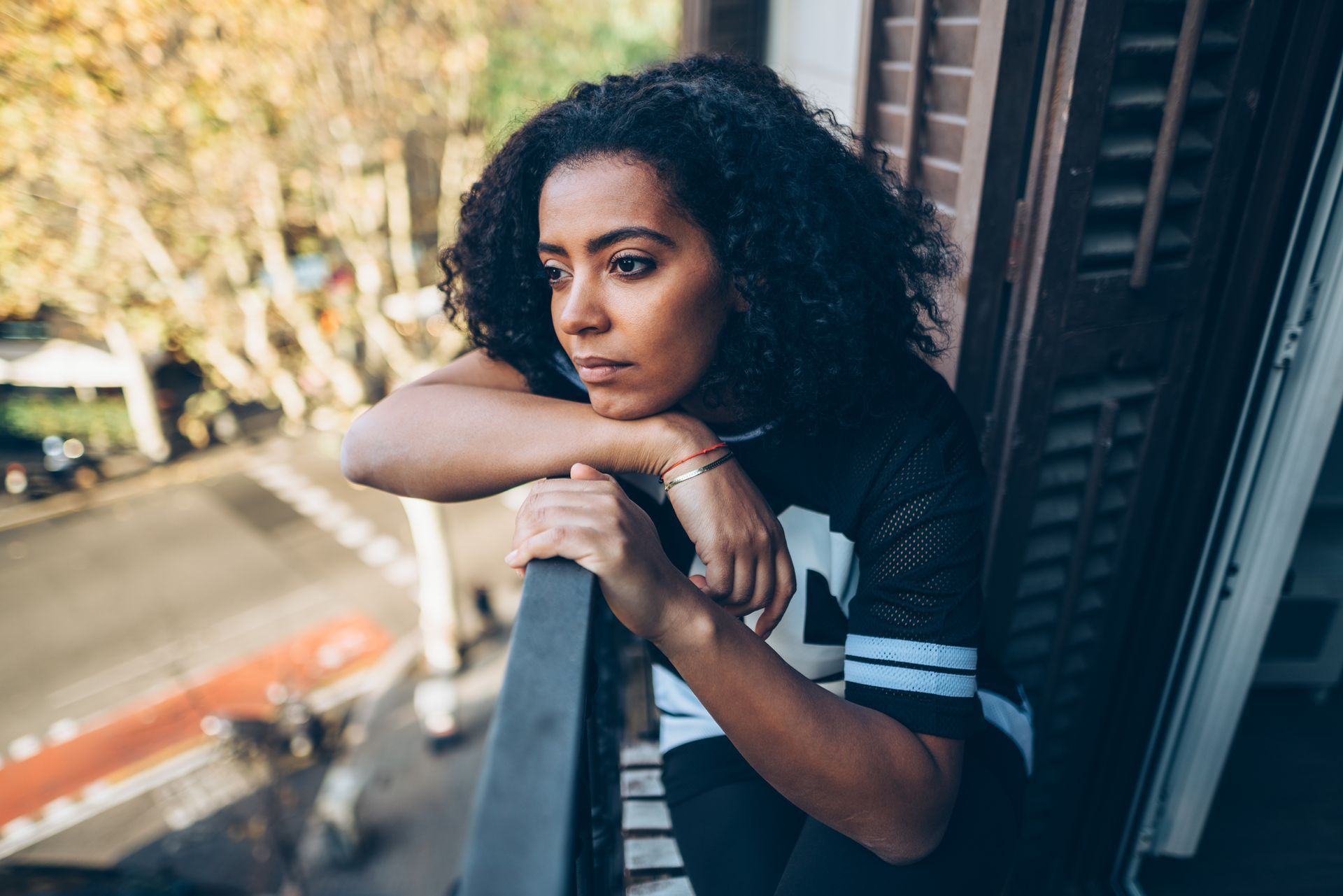 A woman is standing on a balcony looking out the window.