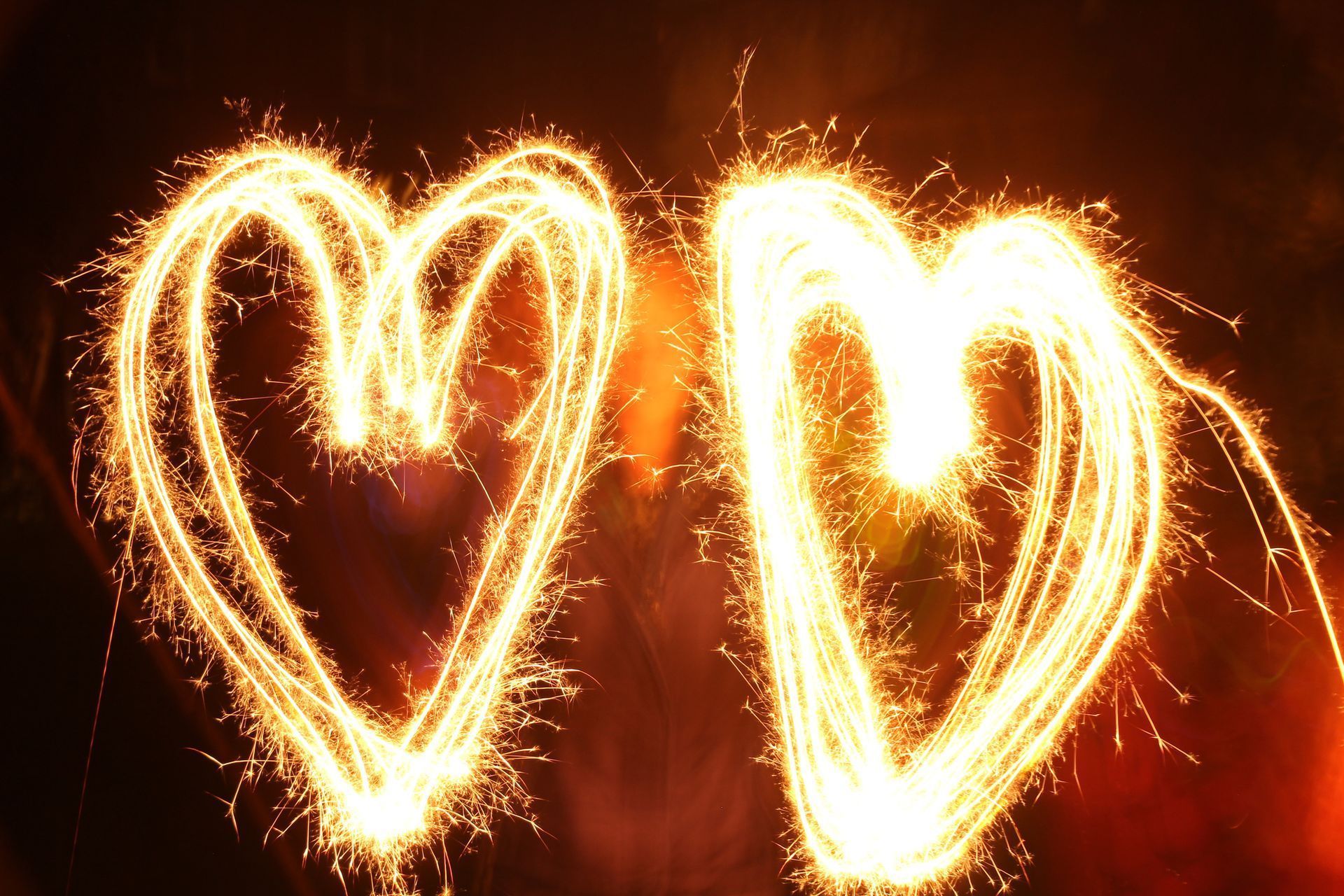 Two hearts made of sparklers on a dark background.