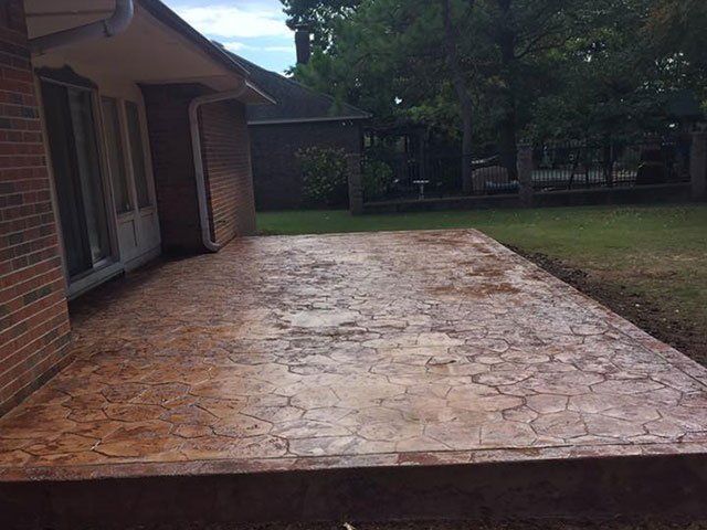 A brick house with a concrete patio in front of it.