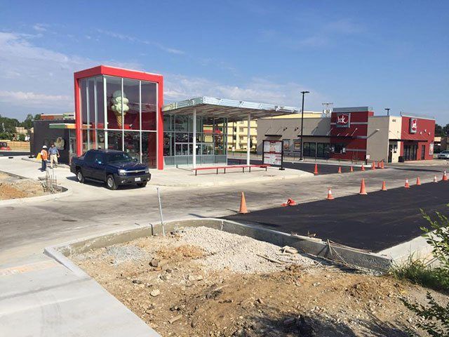 A car is parked in front of a fast food restaurant under construction.