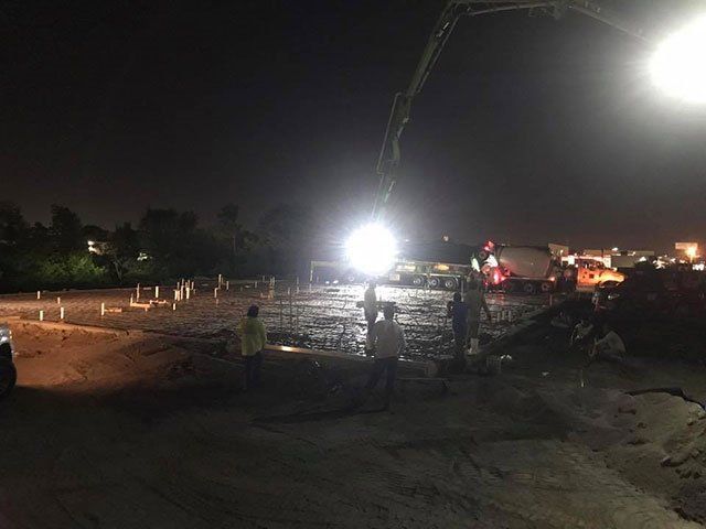 A group of people are working on a construction site at night.