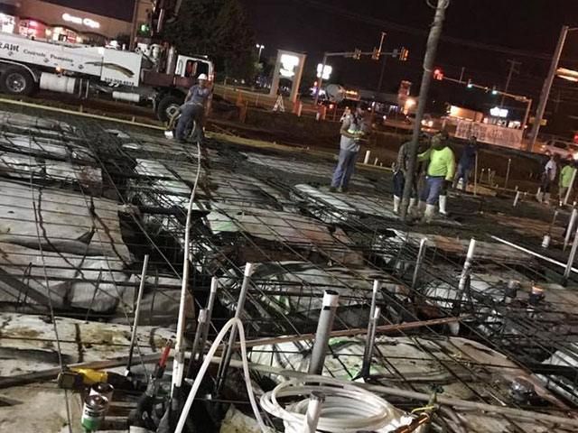 A group of people are working on a construction site at night.
