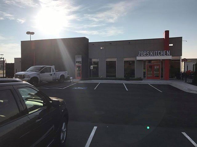 A car is parked in front of a restaurant called tops kitchen.