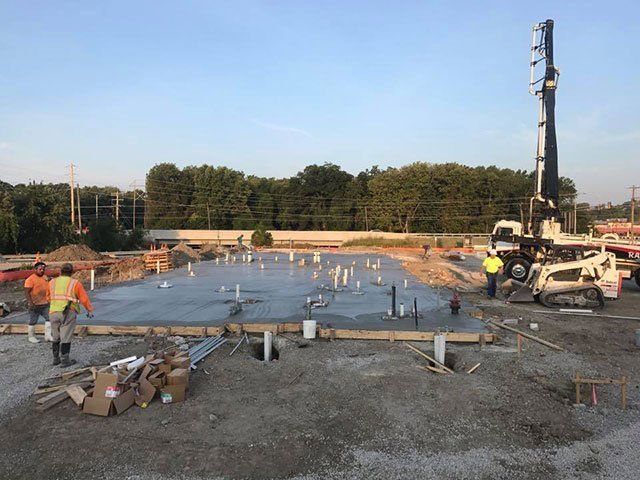 A group of construction workers are working on a concrete floor.