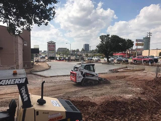 A bulldozer is moving dirt in a parking lot.