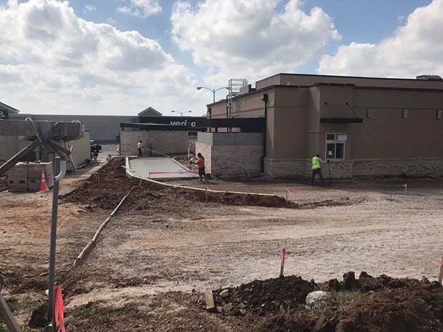 A construction site with a lot of dirt and a building in the background.