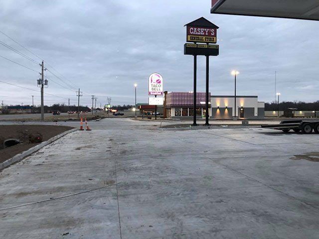 A concrete driveway leading to a gas station with a sign that says ' candy 's ' on it.