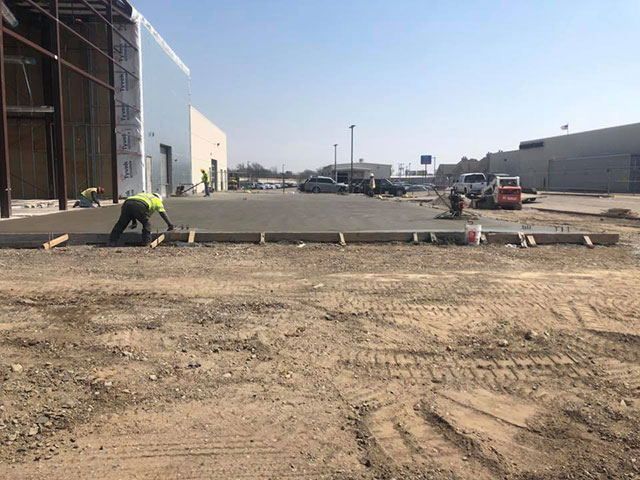 A group of construction workers are working on a concrete driveway.