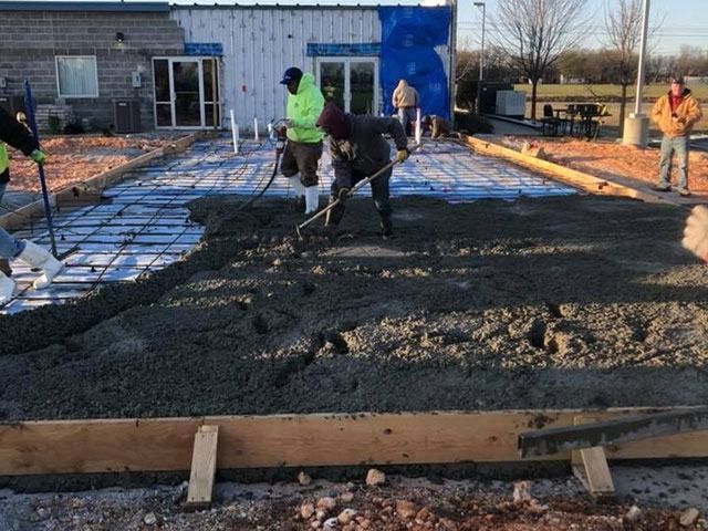 A group of construction workers are working on a concrete floor.