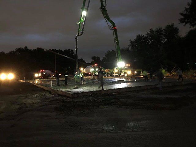 A group of people are working on a construction site at night.