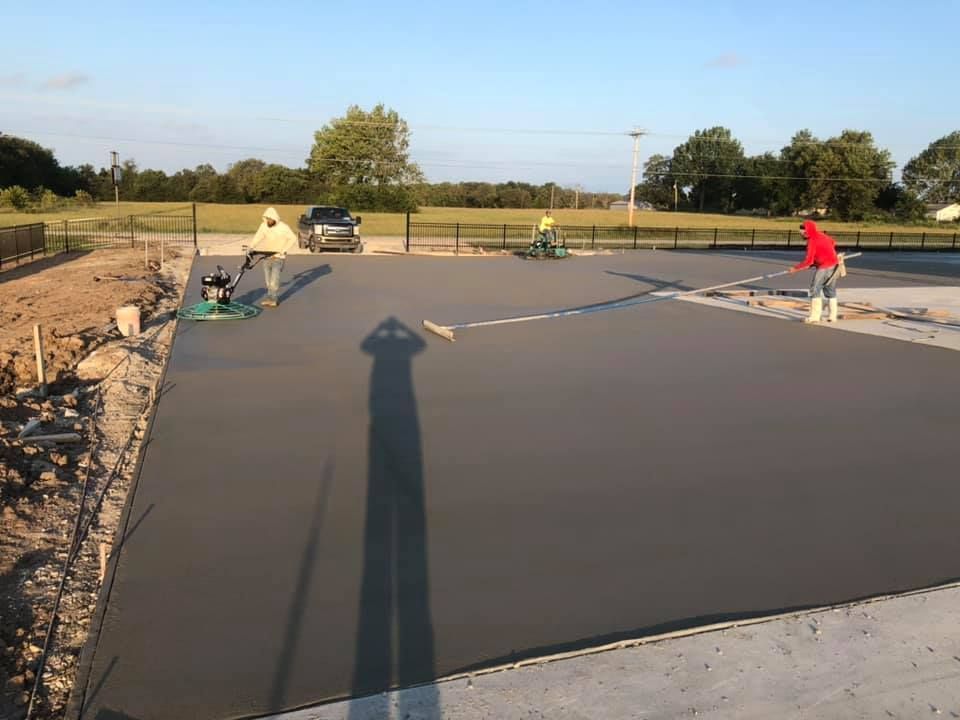 A group of people are working on a concrete driveway.