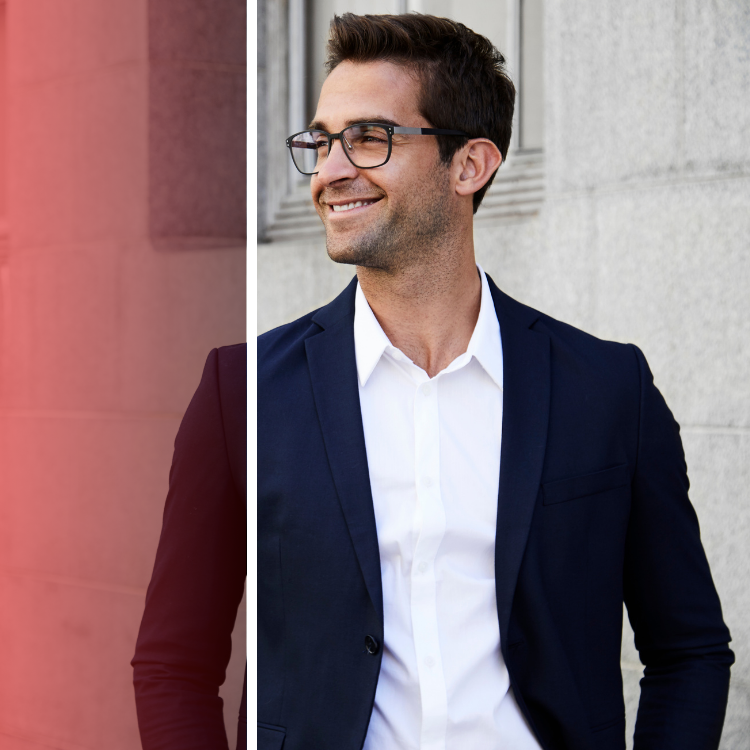 A man wearing glasses and a suit is smiling