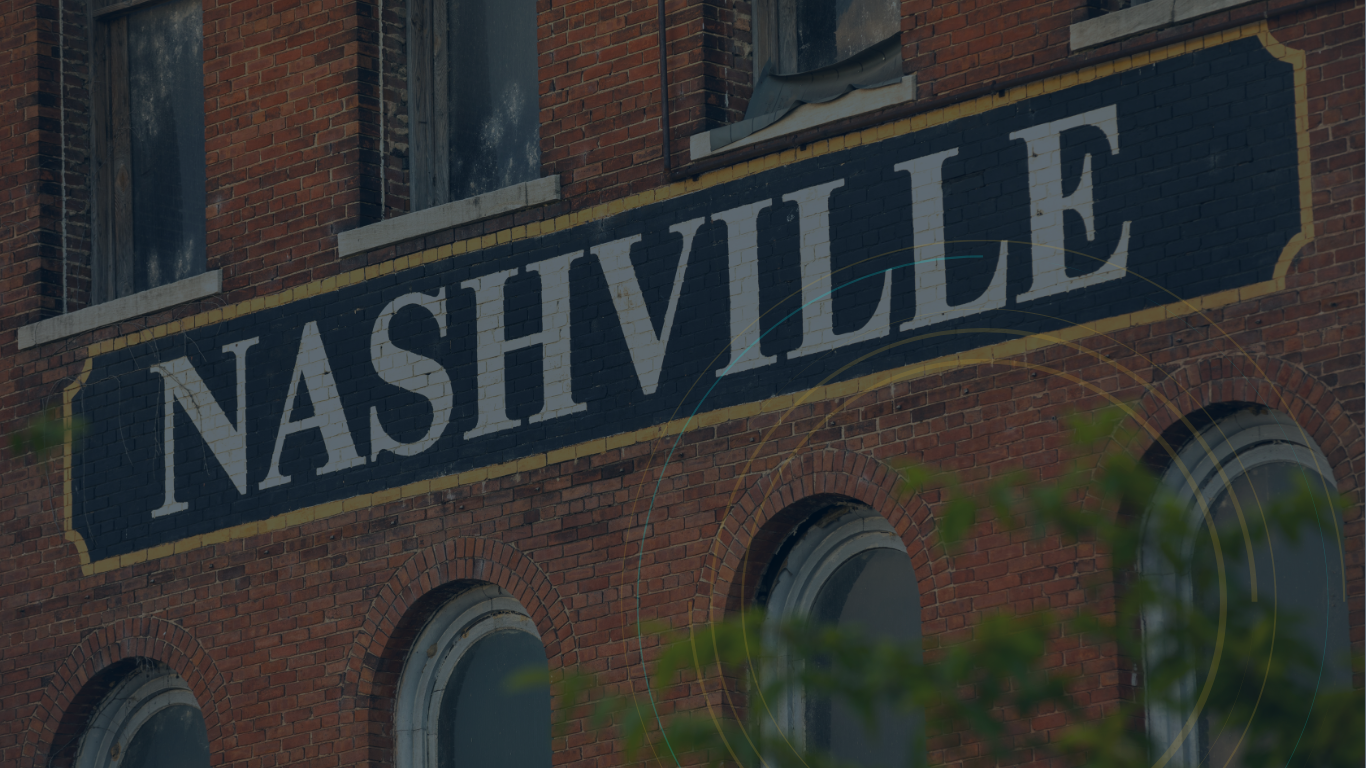 A street sign for nashville is on the side of a brick building.