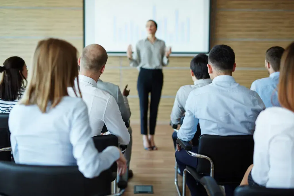 A woman is giving a presentation to a group of people in a conference room.