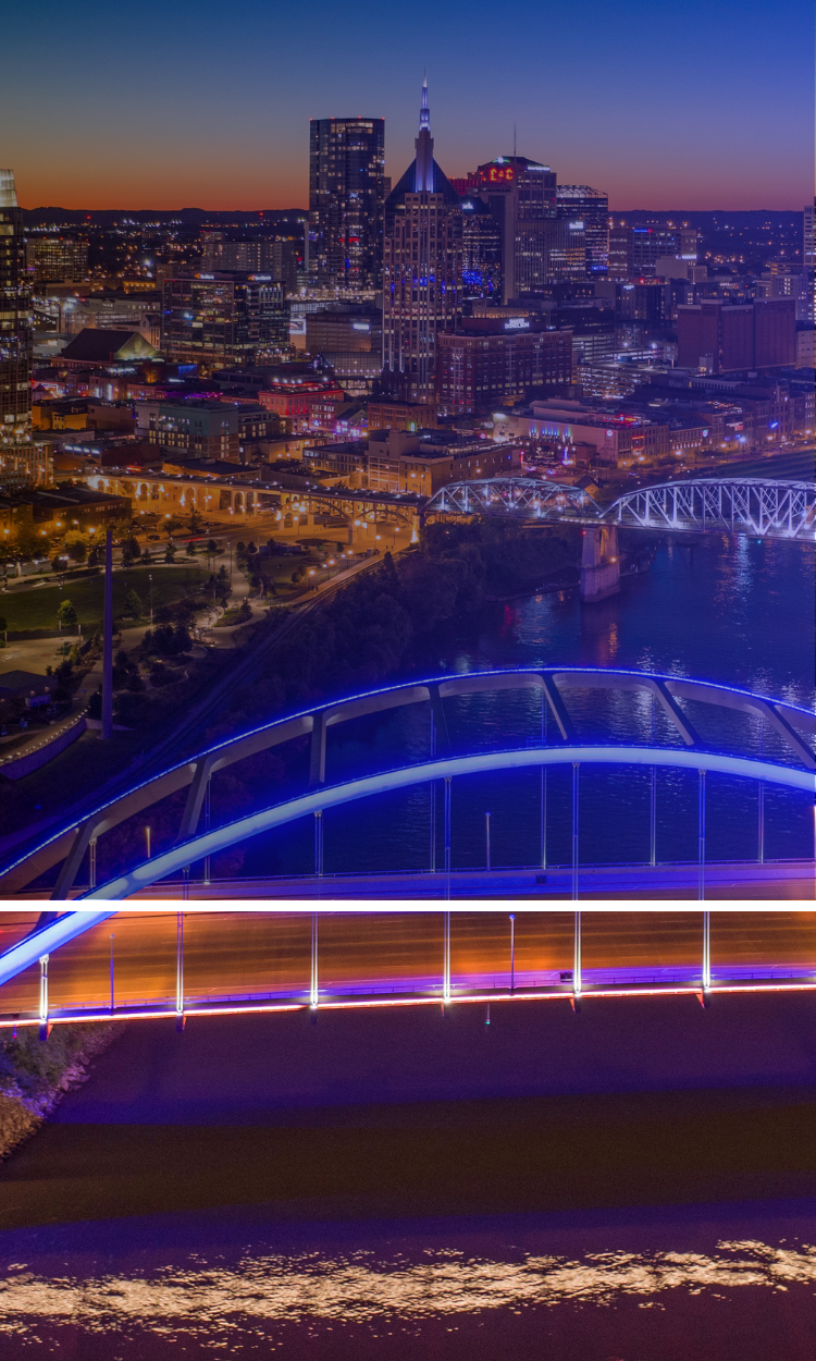A bridge over a river with a city in the background at night.
